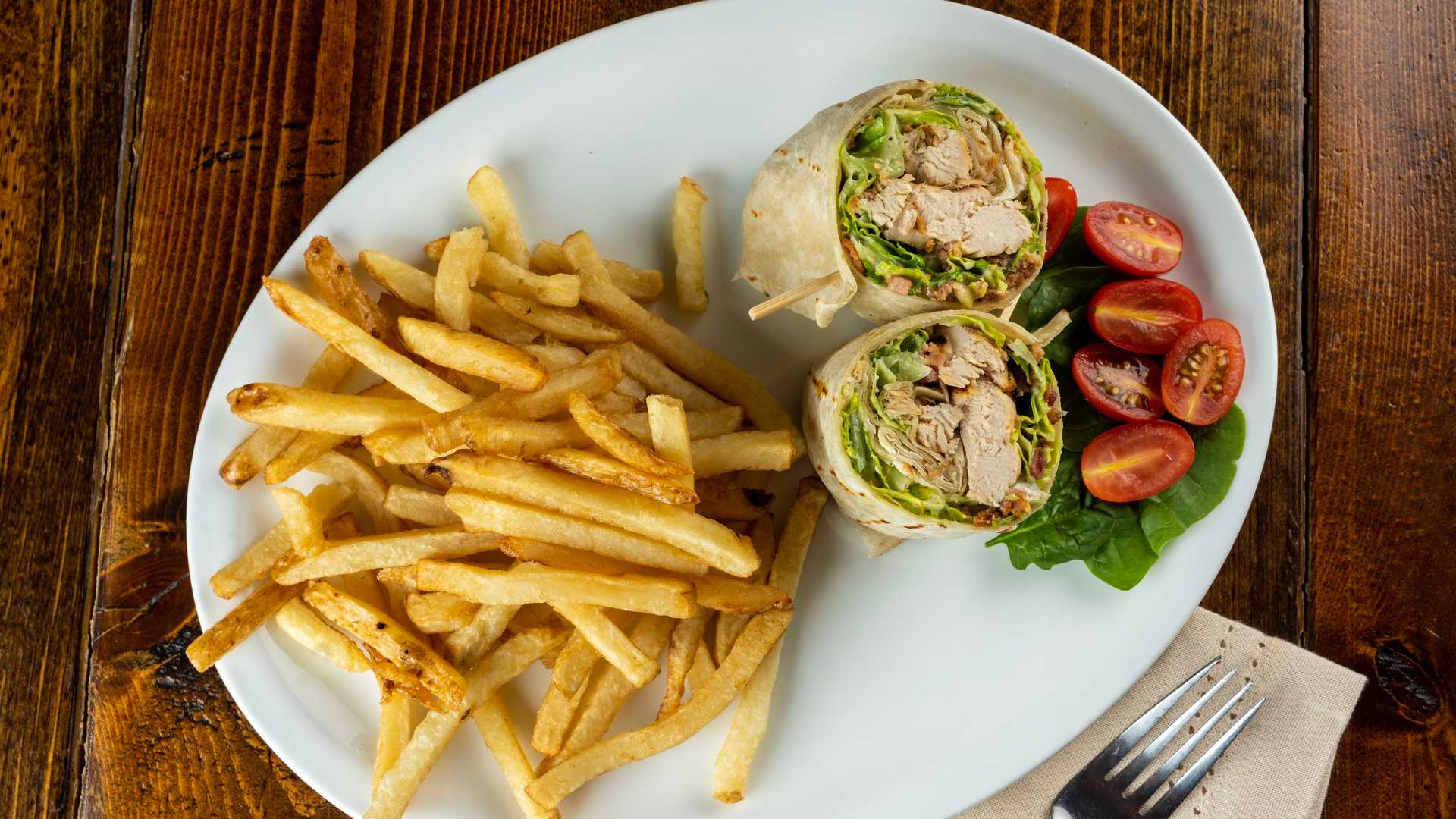Chicken Caesar wrap with fries and bright garden garnish